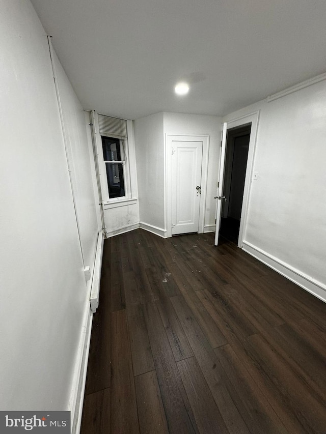 spare room with dark hardwood / wood-style flooring and a baseboard radiator