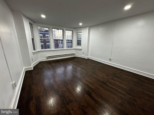 unfurnished room featuring wood-type flooring and a baseboard heating unit