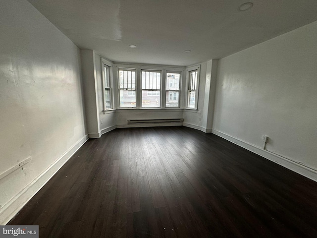 spare room with baseboard heating and dark wood-type flooring