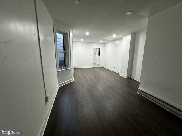 empty room featuring a baseboard radiator and dark hardwood / wood-style floors