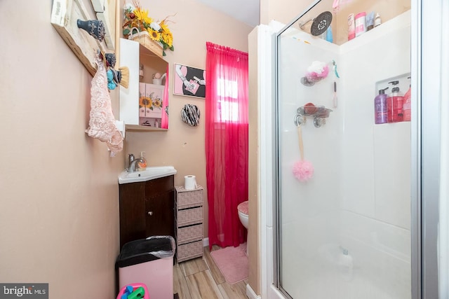 bathroom with vanity, toilet, a shower with shower door, and wood-type flooring