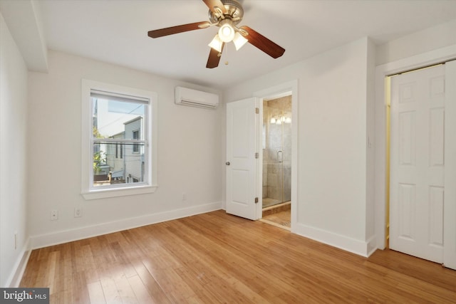 unfurnished bedroom with ensuite bath, ceiling fan, a wall mounted air conditioner, light hardwood / wood-style flooring, and a closet