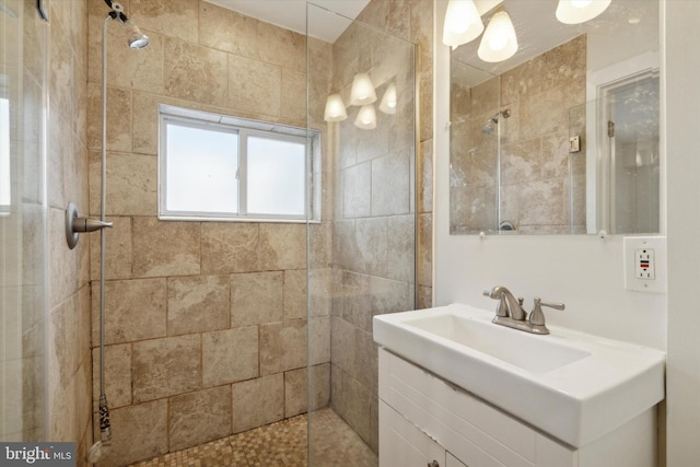 bathroom with a tile shower and vanity