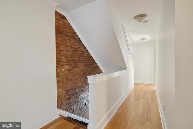 corridor featuring hardwood / wood-style floors and brick wall