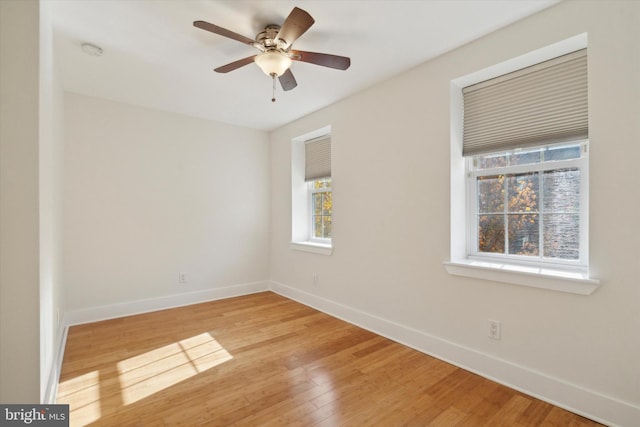 empty room with ceiling fan, wood-type flooring, and a wealth of natural light