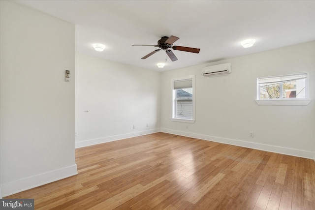 empty room with light hardwood / wood-style floors, a wall unit AC, and ceiling fan