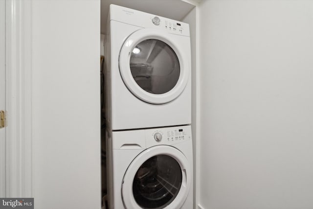 clothes washing area with stacked washing maching and dryer