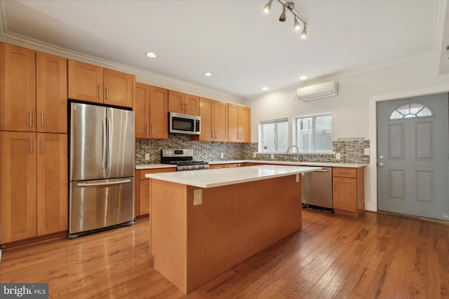 kitchen with light hardwood / wood-style flooring, ornamental molding, a kitchen island, stainless steel appliances, and a wall unit AC