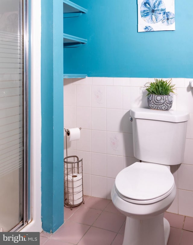 bathroom featuring tile patterned floors, toilet, tile walls, and an enclosed shower