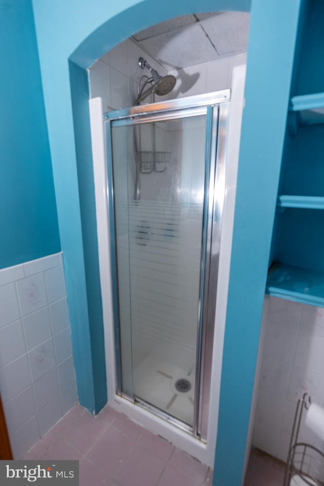 bathroom featuring tile patterned floors, an enclosed shower, and tile walls