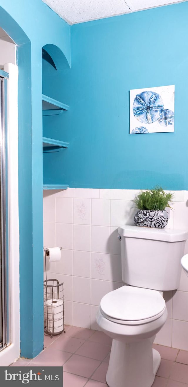 bathroom featuring tile patterned floors, toilet, tile walls, and a textured ceiling