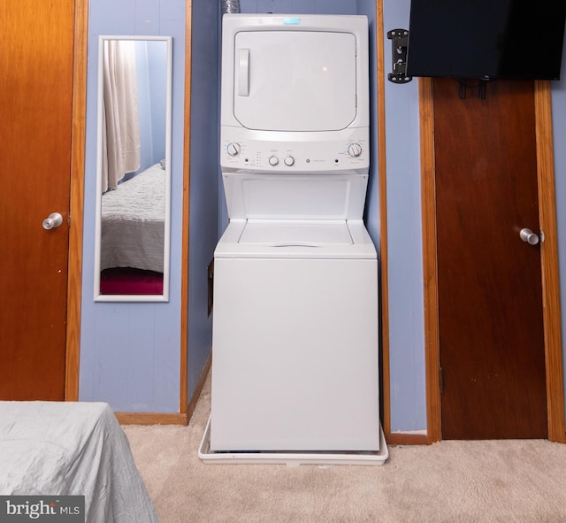 clothes washing area with light colored carpet and stacked washing maching and dryer