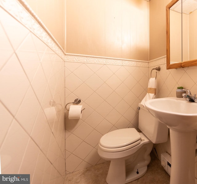 bathroom with sink, toilet, and tile walls