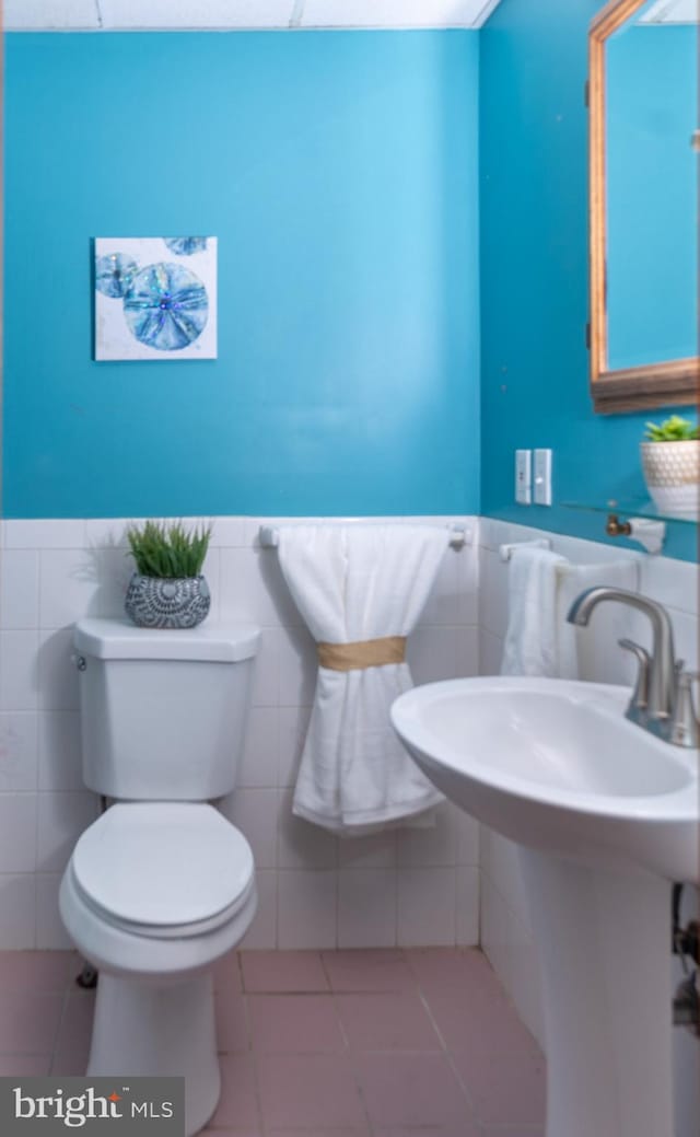 bathroom featuring tile patterned floors, tile walls, and toilet