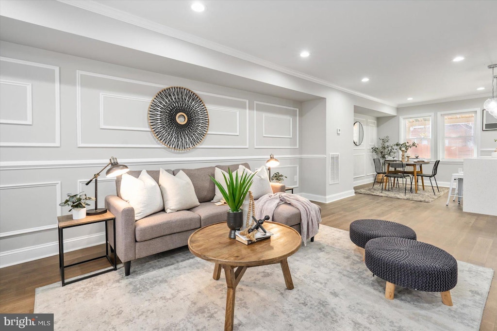 living room with wood-type flooring and ornamental molding