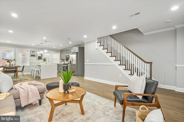 living room with light hardwood / wood-style floors, sink, and crown molding