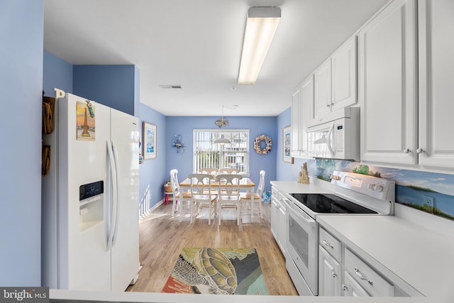 kitchen featuring white cabinets, white appliances, light hardwood / wood-style floors, and hanging light fixtures