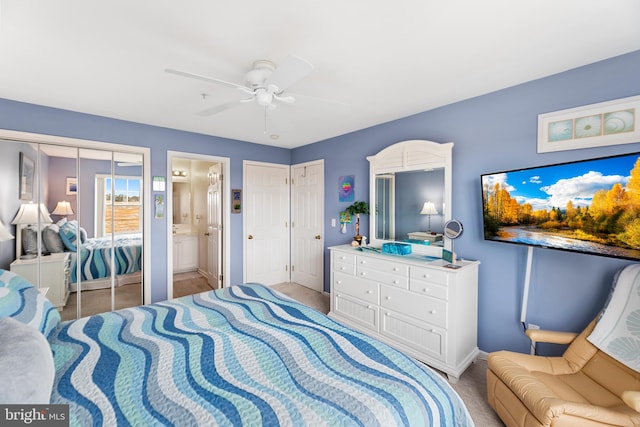 bedroom with ceiling fan, light colored carpet, ensuite bathroom, and two closets