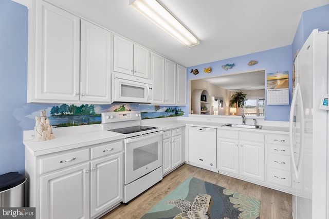 kitchen featuring light wood-type flooring, tasteful backsplash, white appliances, sink, and white cabinets