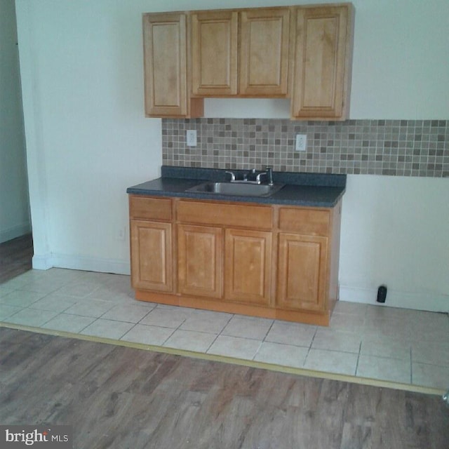 kitchen featuring backsplash, light tile patterned floors, and sink