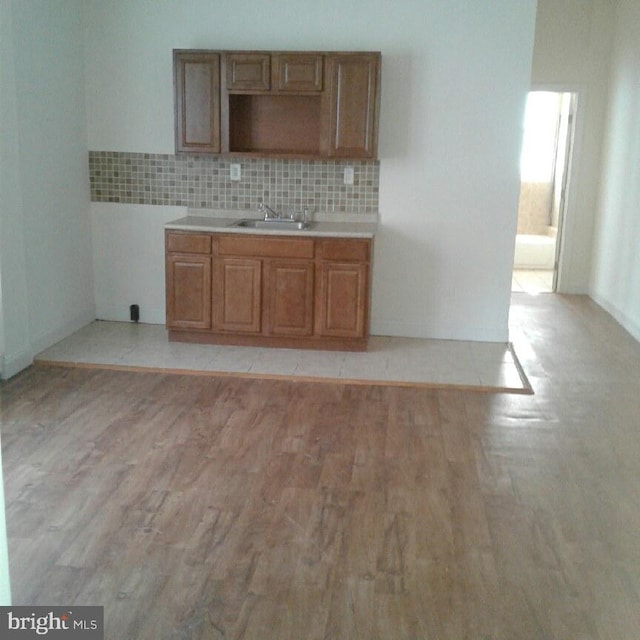 kitchen with tasteful backsplash, light hardwood / wood-style flooring, and sink