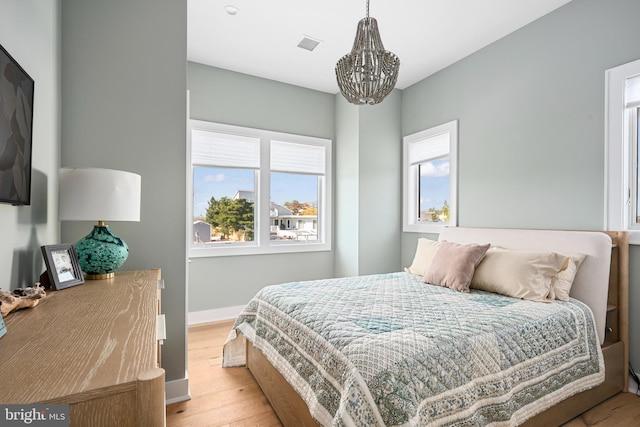 bedroom with light hardwood / wood-style floors and a notable chandelier