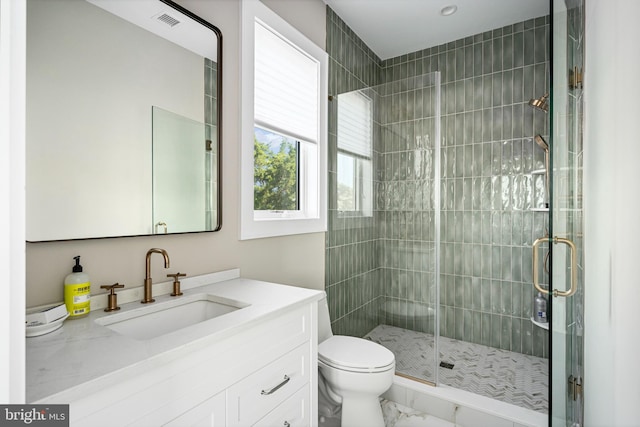 bathroom with a shower with door, vanity, and toilet