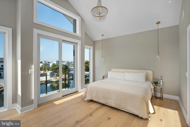 bedroom featuring hardwood / wood-style floors, a water view, access to exterior, and high vaulted ceiling