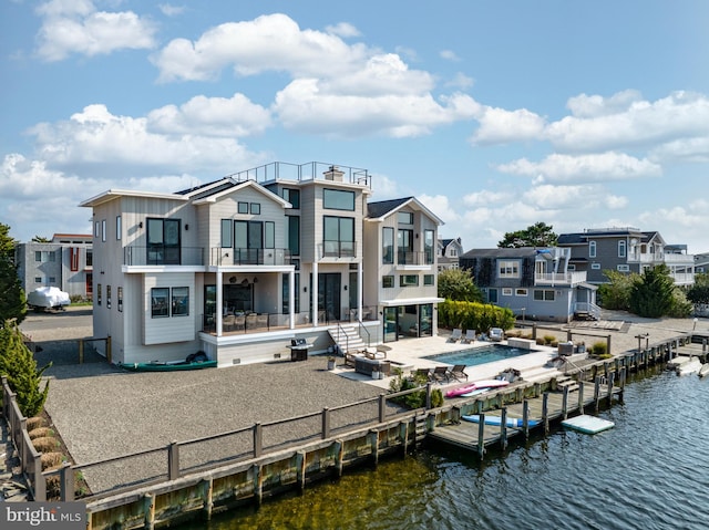 rear view of property with a balcony, a water view, and a patio