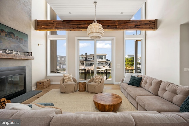 living room featuring a notable chandelier, light hardwood / wood-style floors, a water view, and wooden ceiling