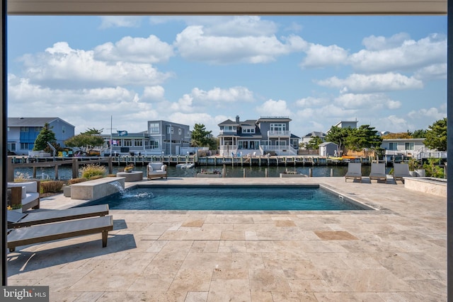 view of swimming pool with pool water feature, a patio area, and a water view