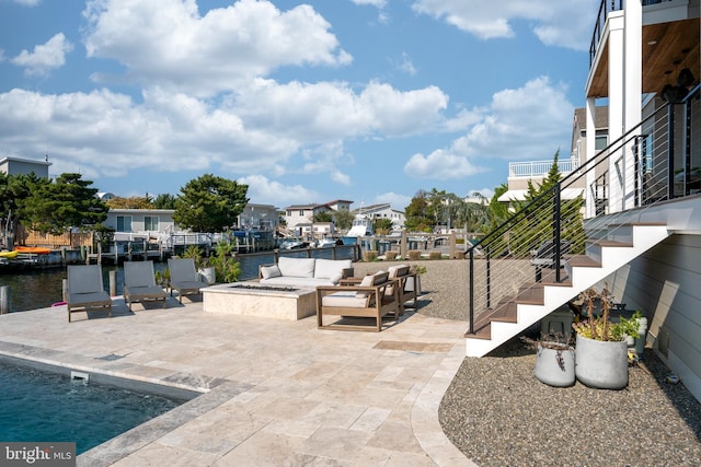 view of patio / terrace featuring a water view and an outdoor living space with a fire pit