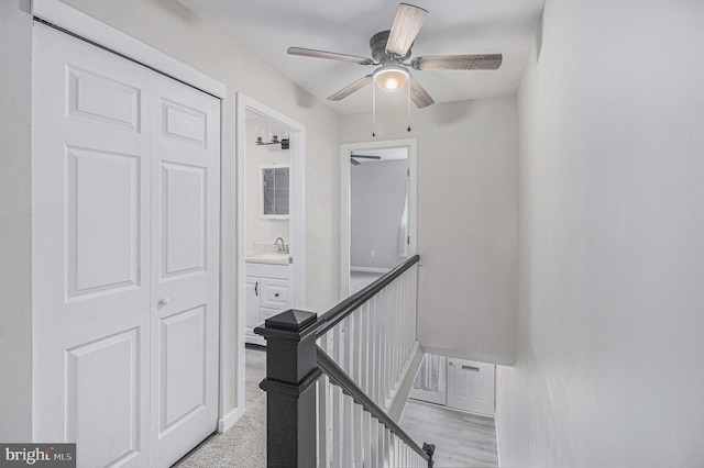 stairway with ceiling fan, sink, and hardwood / wood-style floors