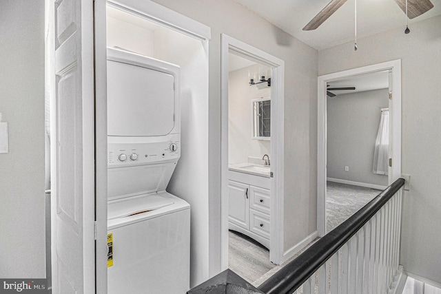 clothes washing area featuring hardwood / wood-style floors, sink, and stacked washer / dryer