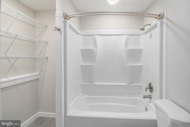 bathroom with wood-type flooring, toilet, and shower / bathtub combination