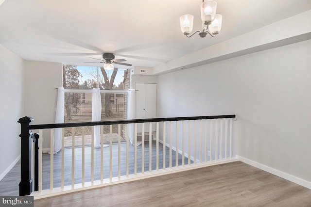 corridor with hardwood / wood-style floors and an inviting chandelier