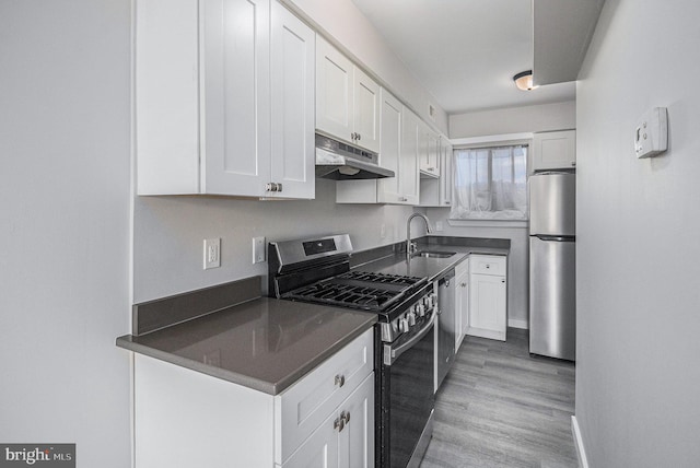 kitchen with white cabinets, appliances with stainless steel finishes, light wood-type flooring, and sink