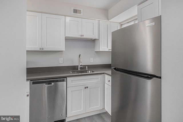 kitchen with white cabinets, light wood-type flooring, stainless steel appliances, and sink