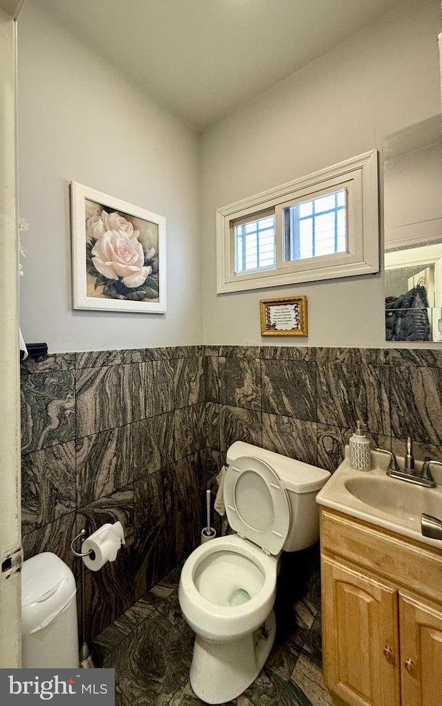 bathroom with vanity, tile walls, and toilet