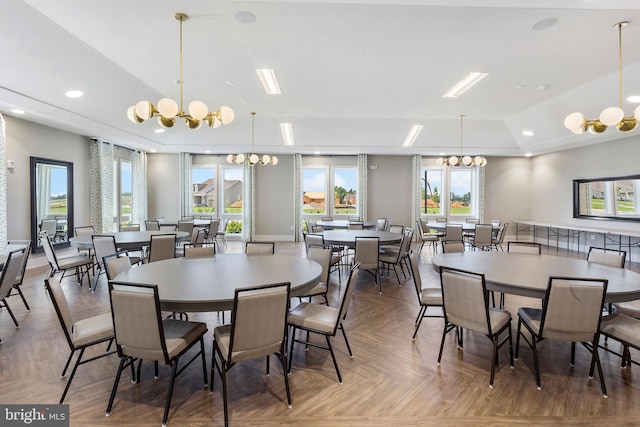 dining room with a chandelier, lofted ceiling, and parquet flooring