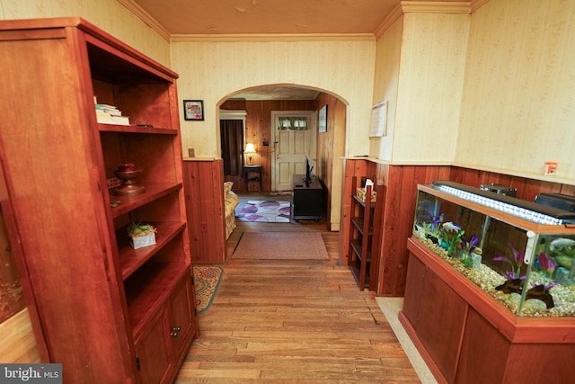 corridor featuring wooden walls, light hardwood / wood-style floors, and crown molding