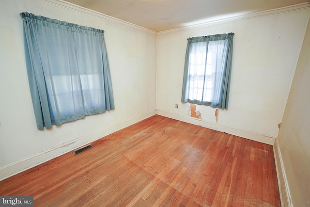 empty room featuring hardwood / wood-style floors and crown molding