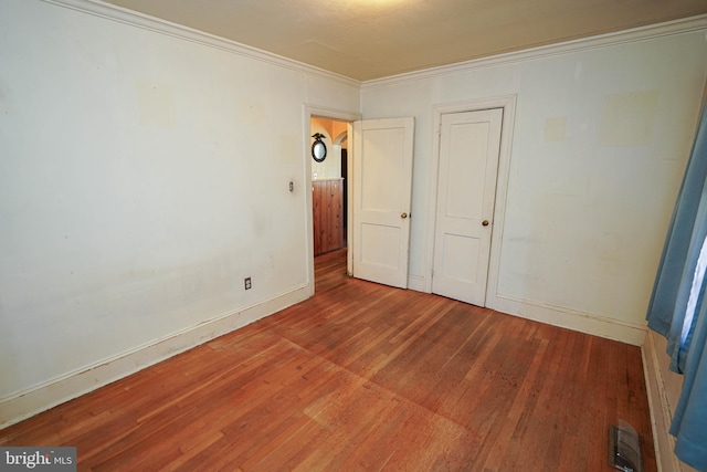 unfurnished bedroom with hardwood / wood-style floors and crown molding