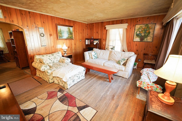 living room with wooden walls, hardwood / wood-style floors, and crown molding