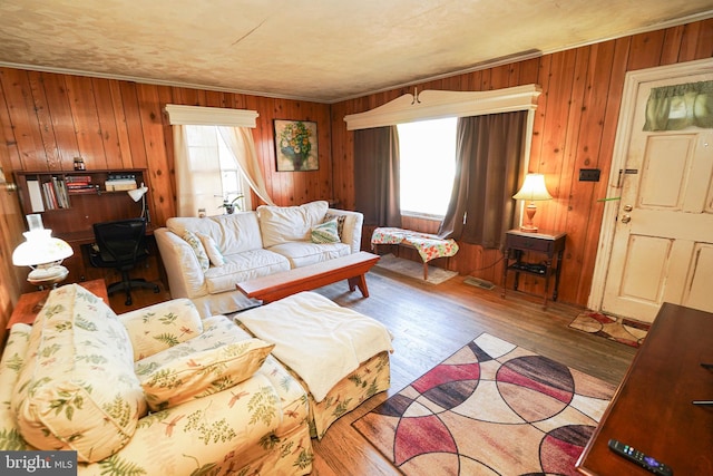 living room with wood walls, hardwood / wood-style floors, and crown molding