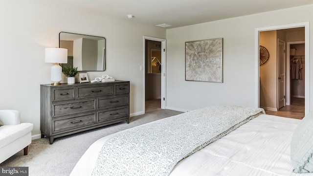 bedroom featuring a walk in closet and light colored carpet