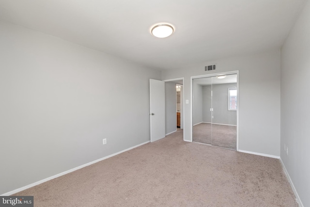 unfurnished bedroom featuring light carpet and a closet