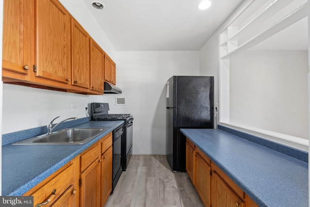 kitchen featuring black appliances, light wood-type flooring, and sink