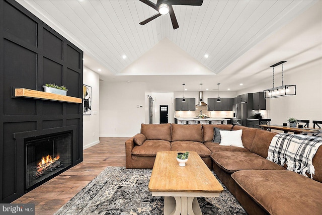 living room with wood ceiling, a large fireplace, vaulted ceiling, ceiling fan, and hardwood / wood-style flooring