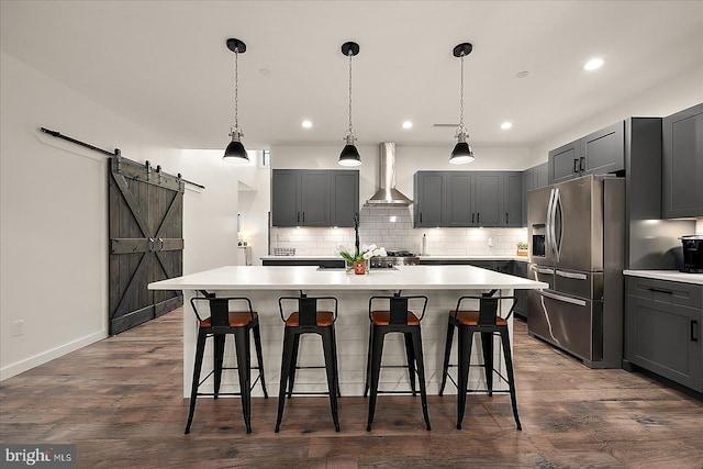 kitchen featuring a center island, wall chimney exhaust hood, a barn door, dark hardwood / wood-style flooring, and stainless steel fridge with ice dispenser